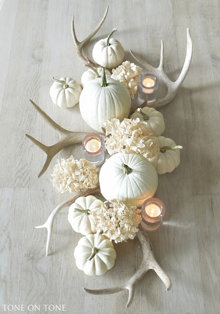 Antlers, similar to candlesticks, are a great way to add height and dimension to your Thanksgiving table. Whitewashed antlers are a modern take on the woodsy decor while the natural brown look is more rustic. Fill in the table runner of decor with pumpkins, candles and greenery.