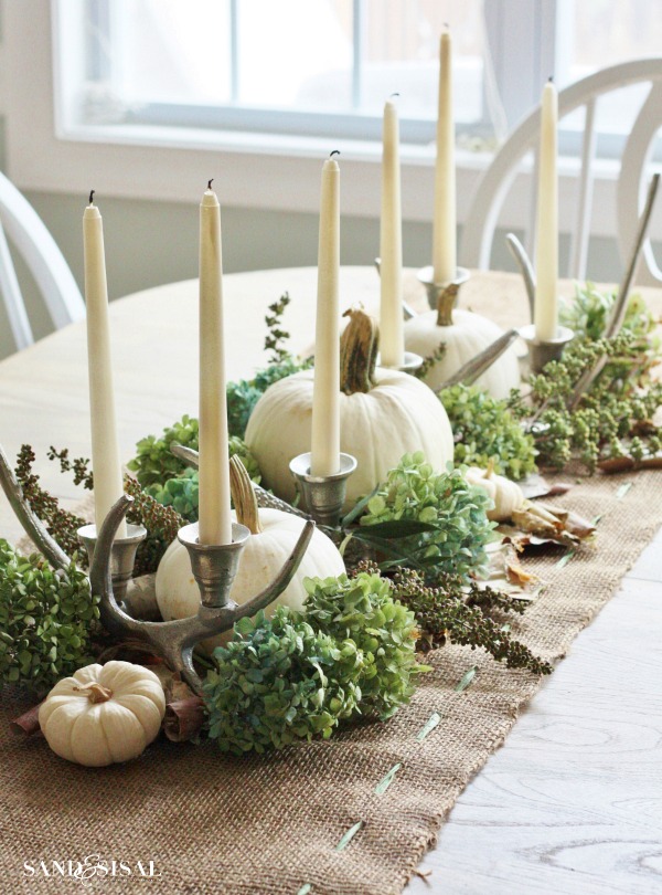 Antlers, similar to candlesticks, are a great way to add height and dimension to your Thanksgiving table. Whitewashed antlers are a modern take on the woodsy decor while the natural brown look is more rustic. Fill in the table runner of decor with pumpkins, candles and greenery.