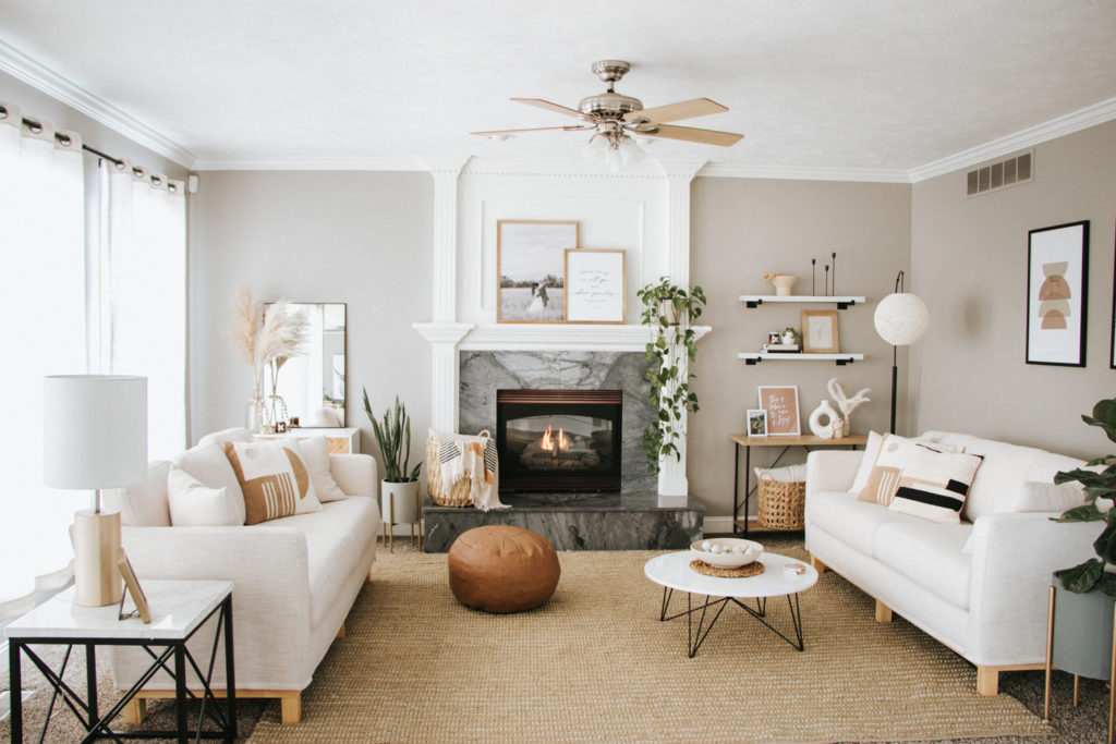 Modern boho living room with plants, round coffee table, natural rug, and cream couches | The Anastasia Co